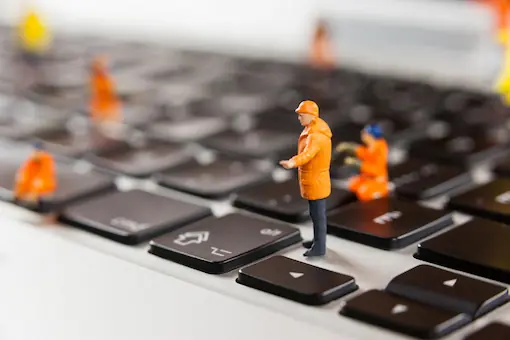 Figuras de trabajadores reparando un teclado, representando el mantenimiento web
